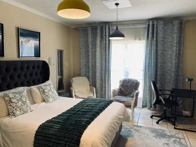 a bedroom with a bed and a desk and a window at Hatfield, Grosvenor Private apartment. in Pretoria