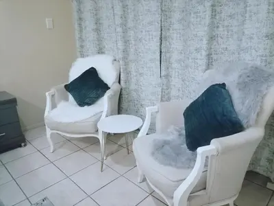 two chairs and a table in a living room at Hatfield, Grosvenor Private apartment. in Pretoria