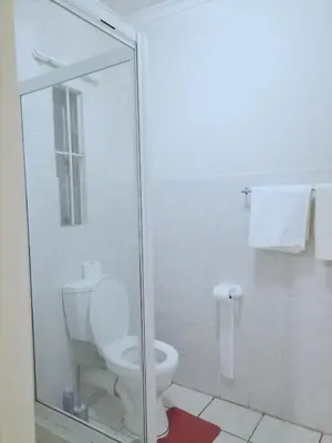 a bathroom with a toilet and a glass shower at Hatfield, Grosvenor Private apartment. in Pretoria