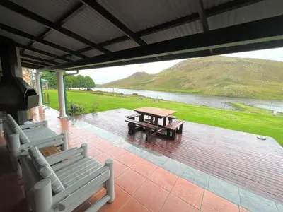 a picnic table and chairs on a patio with a lake at Le Rendezvous in Dullstroom