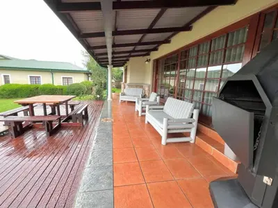 a patio with benches and a table and a fireplace at Le Rendezvous in Dullstroom