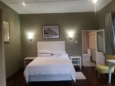 a bedroom with a white bed and a bathroom at Metsing at Harties in Hartbeespoort