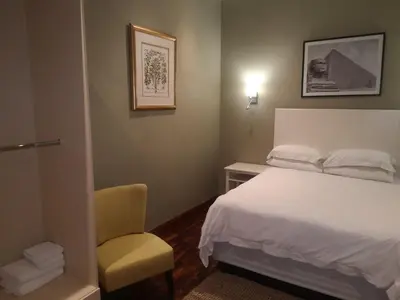 a bedroom with a white bed and a chair at Metsing at Harties in Hartbeespoort