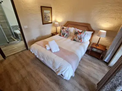 a bedroom with a large bed with two pillows at Migrate Portfolio in Dullstroom