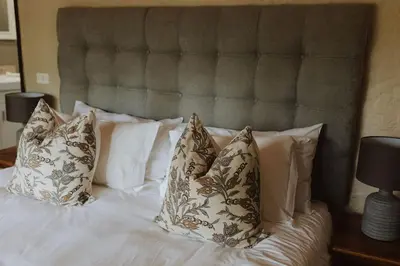a bed with white pillows and a headboard at Migrate Portfolio in Dullstroom
