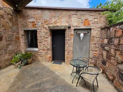 a patio with two chairs and a table in front of a stone wall at Migrate Portfolio in Dullstroom