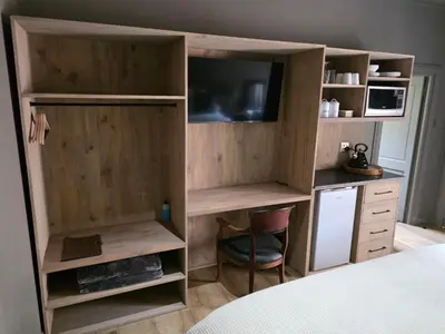 a room with a bed and a desk and a tv at Migrate Portfolio in Dullstroom