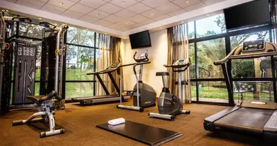 a gym with treadmills and exercise equipment in a room with windows at Garden Court Hatfield in Pretoria