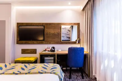 a hotel room with a desk and a tv at Garden Court Hatfield in Pretoria