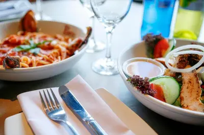 a table with two bowls of food and a plate of pasta at Garden Court Polokwane in Polokwane