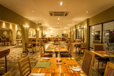 a dining room with wooden tables and chairs at Garden Court Polokwane in Polokwane