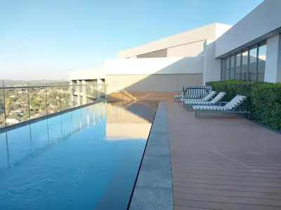 a building with a swimming pool and some chairs at Menlyn Apartment - Black Marble in Pretoria
