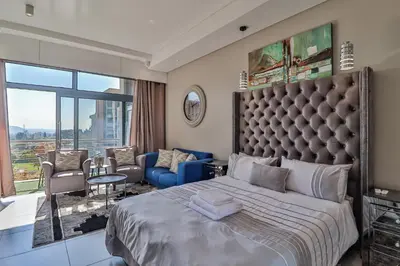 a bedroom with a large bed and a living room at 301 Menlyn Maine Trilogy Apartment in Pretoria