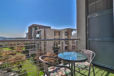 a patio with a table and chairs on a balcony at 301 Menlyn Maine Trilogy Apartment in Pretoria