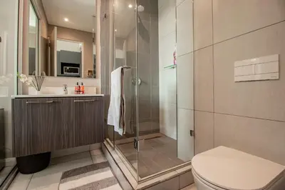 a bathroom with a shower and a toilet and a sink at 301 Menlyn Maine Trilogy Apartment in Pretoria