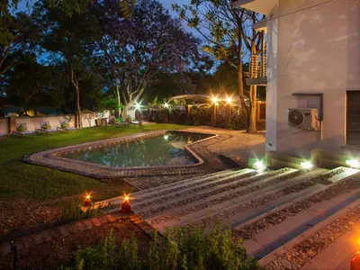 a backyard with a swimming pool at night at The Coral Tree in Nelspruit