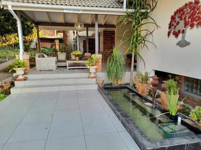 a patio with a pond in the middle of a house at The Coral Tree in Nelspruit