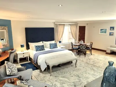 a bedroom with a large bed and a table and chairs at The Coral Tree in Nelspruit