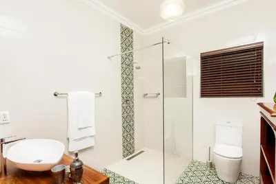 a bathroom with a toilet and a glass shower at The Coral Tree in Nelspruit