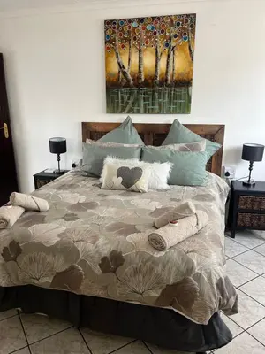 a bed with two pillows and a painting on the wall at Rustic red in Benoni