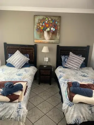 a bedroom with two beds and a painting on the wall at Rustic red in Benoni