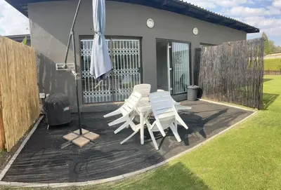 two white chairs and an umbrella on a patio at Rustic red in Benoni