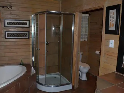 a bathroom with a shower and a tub and a toilet at Bohm's Zeederberg Country House in Hazyview