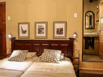 a bedroom with a bed with three pictures on the wall at Bohm's Zeederberg Country House in Hazyview