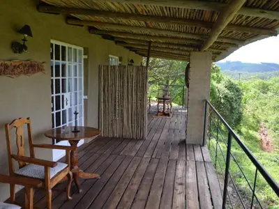 a porch of a house with a table and chairs at Bohm's Zeederberg Country House in Hazyview