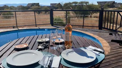 a table with plates and glasses and a bottle of wine at Luna rossa 19 Zebula golf course and spa resort in Mabula