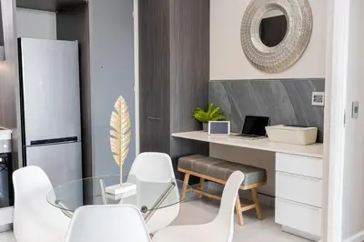 a dining room with a desk and white chairs at Menlyn Apartment - 2 Bedroom Apartment in Pretoria
