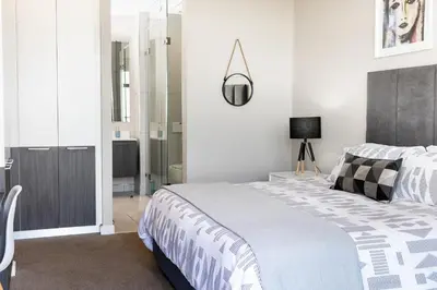 a white bedroom with a bed and a lamp at Menlyn Apartment - 2 Bedroom Apartment in Pretoria