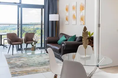 a living room with a couch and a table and chairs at Menlyn Apartment - 2 Bedroom Apartment in Pretoria