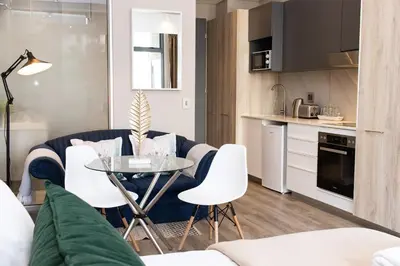 a kitchen and a living room with a table and chairs at Menlyn Residence - Studio Apartment in Pretoria