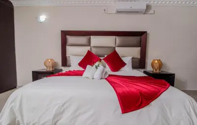a bedroom with a large white bed with red pillows at ASANTE MOUNTAIN LODGE in Hazyview