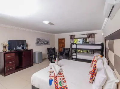 a bedroom with a bed and a tv and a bed at ASANTE MOUNTAIN LODGE in Hazyview