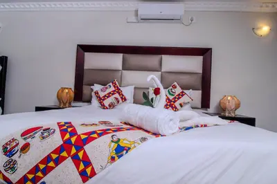a bedroom with a large bed with a bedspread and pillows at ASANTE MOUNTAIN LODGE in Hazyview
