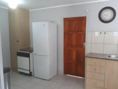 a kitchen with a refrigerator and a clock on the wall at Wild Escape in Marloth Park