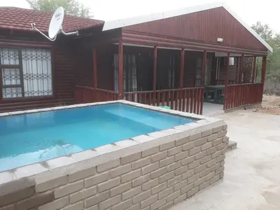 a swimming pool in front of a house at Wild Escape in Marloth Park