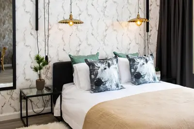 a bedroom with a bed with pillows and a table at Menlyn Apartment - Marble Print in Pretoria