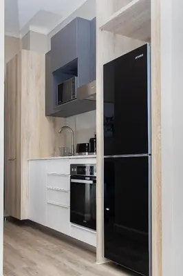 a kitchen with a black refrigerator and white cabinets at Menlyn Apartment - Marble Print in Pretoria