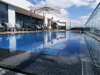 a swimming pool with a umbrella and chairs and a building at Menlyn Apartment - Marble Print in Pretoria
