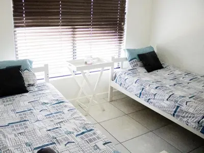 a bedroom with two beds and a table and a window at 150 The Blyde Crystal Clear Lagoon 3 Bedroom Garden Apartment in Pretoria