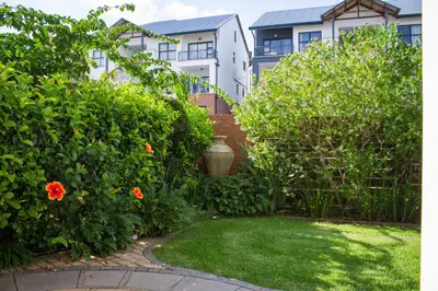 a garden with orange flowers in front of a building at 150 The Blyde Crystal Clear Lagoon 3 Bedroom Garden Apartment in Pretoria