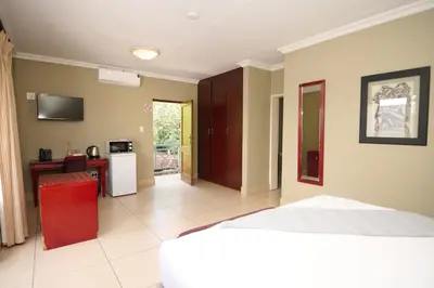 a bedroom with a bed and a kitchen with a table at Tamboti Guest Lodge in Pretoria