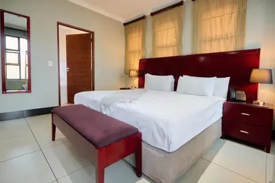 a large bedroom with a large bed and a bench at Tamboti Guest Lodge in Pretoria