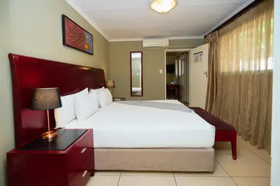 a bedroom with a large bed and a table with a lamp at Tamboti Guest Lodge in Pretoria
