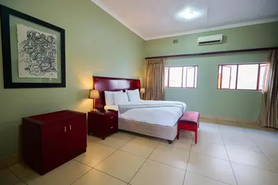 a bedroom with a bed and a table and a chair at Tamboti Guest Lodge in Pretoria