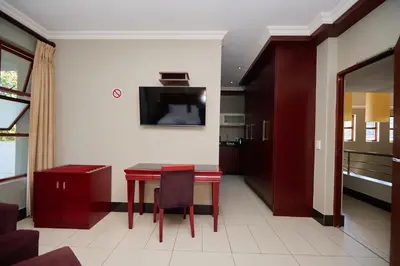 a living room with a red table and a tv at Tamboti Guest Lodge in Pretoria