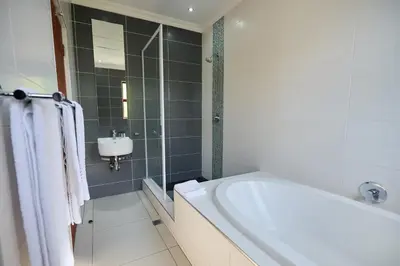 a white bathroom with a tub and a sink at Tamboti Guest Lodge in Pretoria